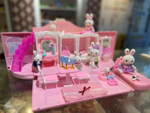 Childs toy rabbit family figures displayed in pink dolls house 