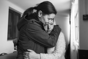 Black and white image of two women hugging, one a distraught Ukrainian refugee, given refuge by FARA charity