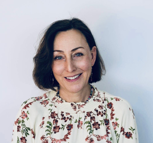 a photo of karen bendell, a woman with brown hair smiling at the camera against a plain backdrop