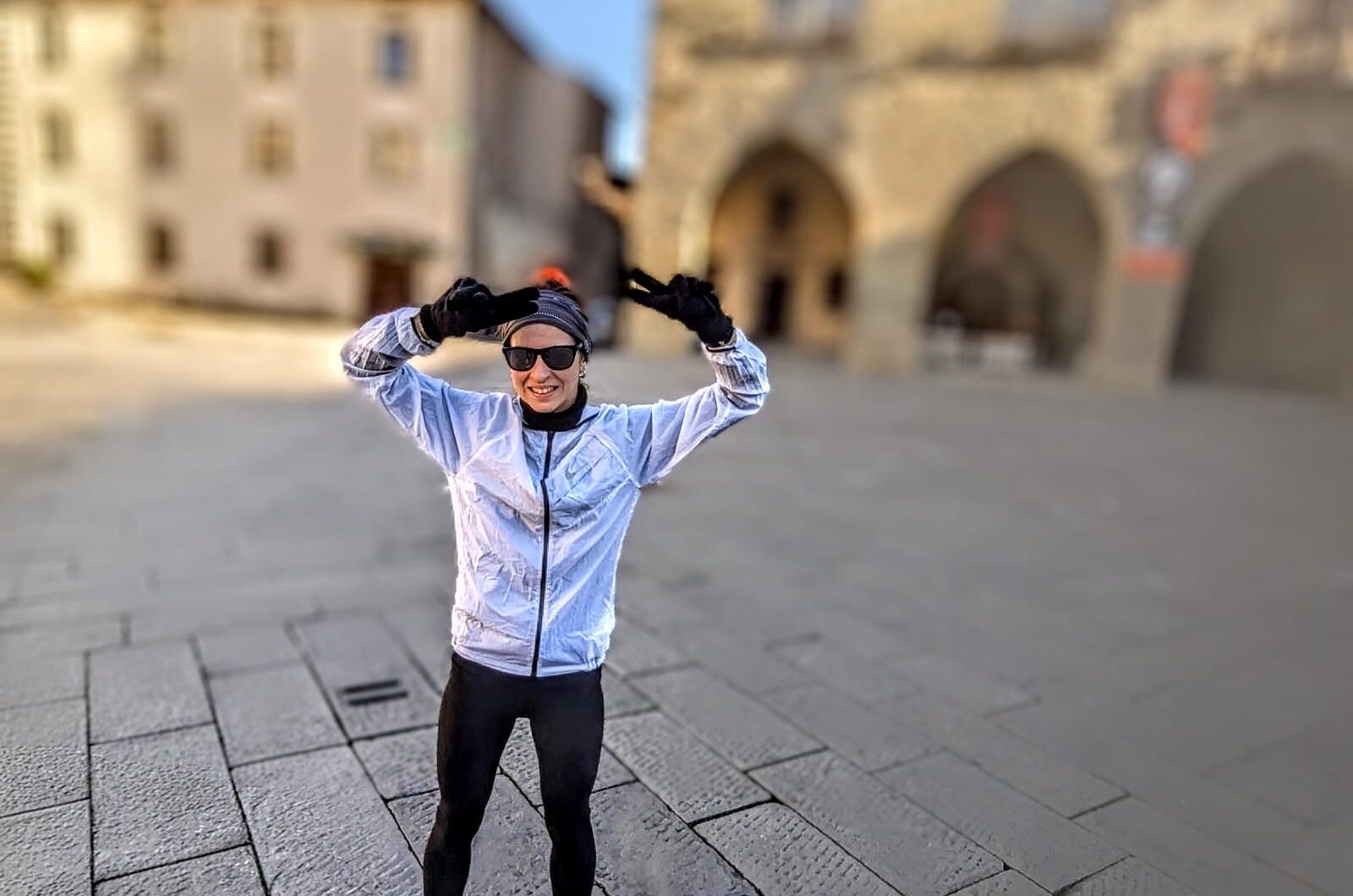 Photo of a young woman in full running gear with two fingers raised in a peace sign