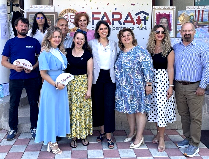 A group of people stand infront of a sign saying FARA smiling at the camera